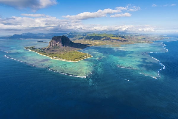 Aerial view of the volcanic island of Mauritius with pristine beaches, crystal-clear waters, and lush green landscapes, inviting travelers to explore its natural beauty.