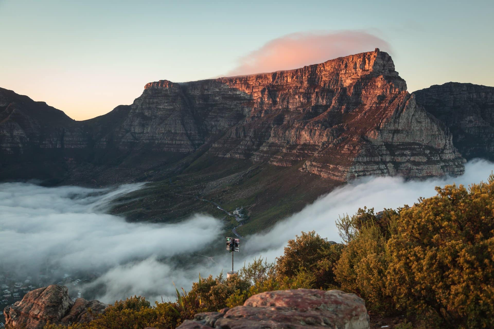 Table Mountain, South Africa view of mist, sunset, vegetation and cliff sides. Cape town