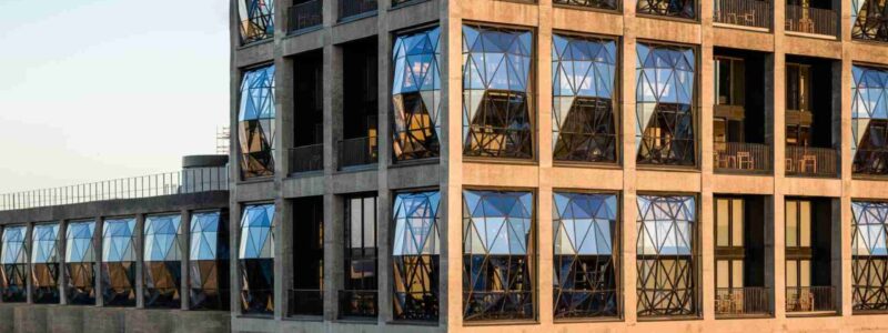 Exterior view of The Silo Hotel in Cape Town, showcasing its unique geometric windows and modern industrial design at sunset.