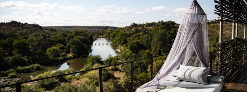 Outdoor lounge area with a mosquito bed overlooking a river valley, Singita Lebombo, Kruger National Park, South Africa.