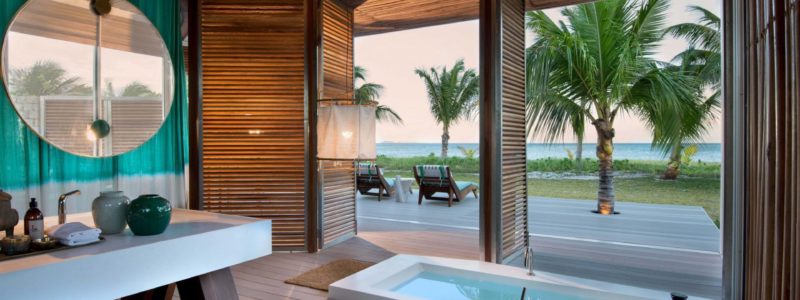 Luxury villa interior, African style design, Bath and decking area overlooking African beach and sea. Time + Tide villa.