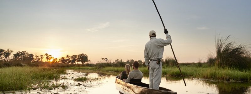 Couple led by tour guide on romantic African safari boat trip. With best Botswana views and scenery.