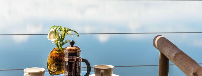 Luxury Kenya Safari The Cliff table with coffee and luxury coffee pot overlooking beautiful African water with cliffs in the background.