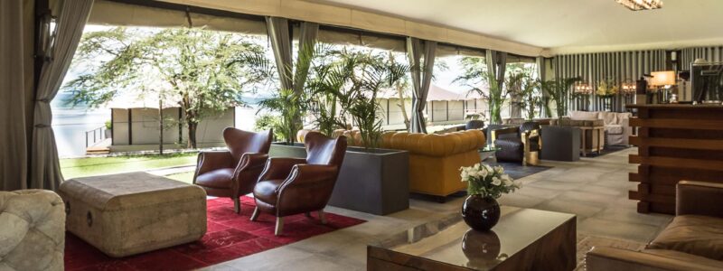 Luxury Kenya Safari The Cliff Interior with cultural furniture, tables and bar area with a view of African landscapes and ocea.