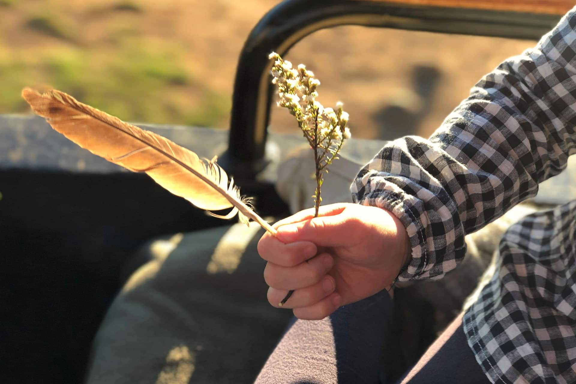 Child holding a feather and wildflowers during a family safari adventure in Africa.