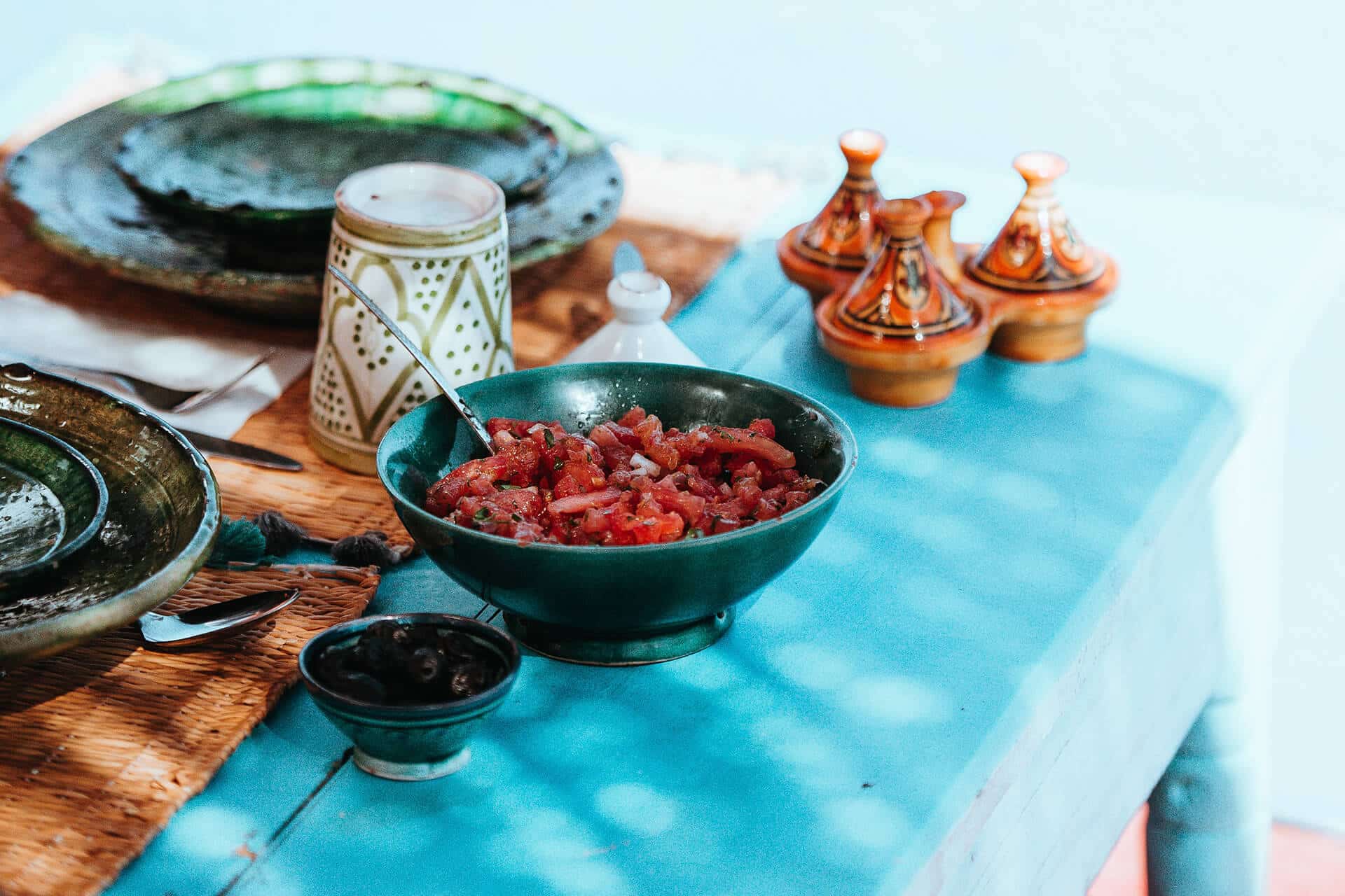 Traditional African dishes served on a vibrant table with ceramic plates, tagines, and a bowl of fresh tomato salad, capturing the essence of a culinary safari experience.