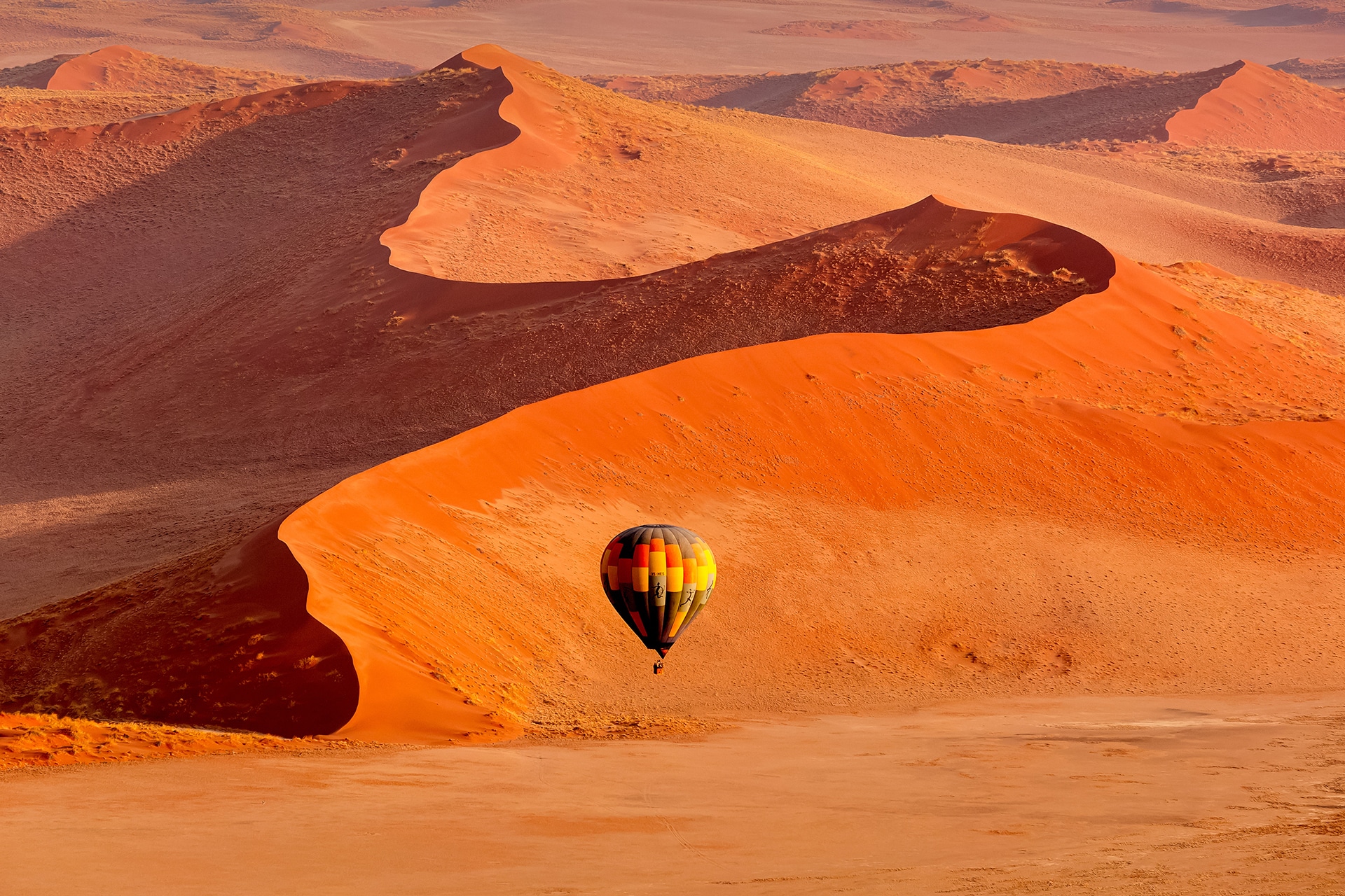 Hot air balloon flying above the fiery red sand dunes of Namibia&rsquo;s Namib Desert, capturing the dramatic landscapes and sense of adventure the country is known for.