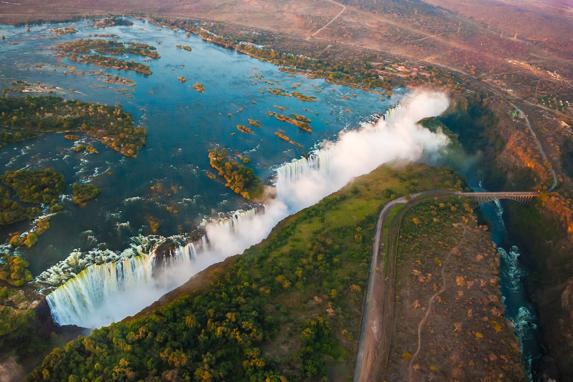 Aerial view of Victoria Falls in Zambia, surrounded by lush greenery and rugged terrain, an iconic natural wonder near top luxury safari destinations.