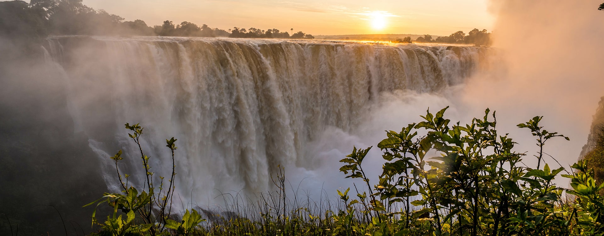 The mighty Victoria Falls scenic view of sunset on the falls surrounded by lush green vegetation.