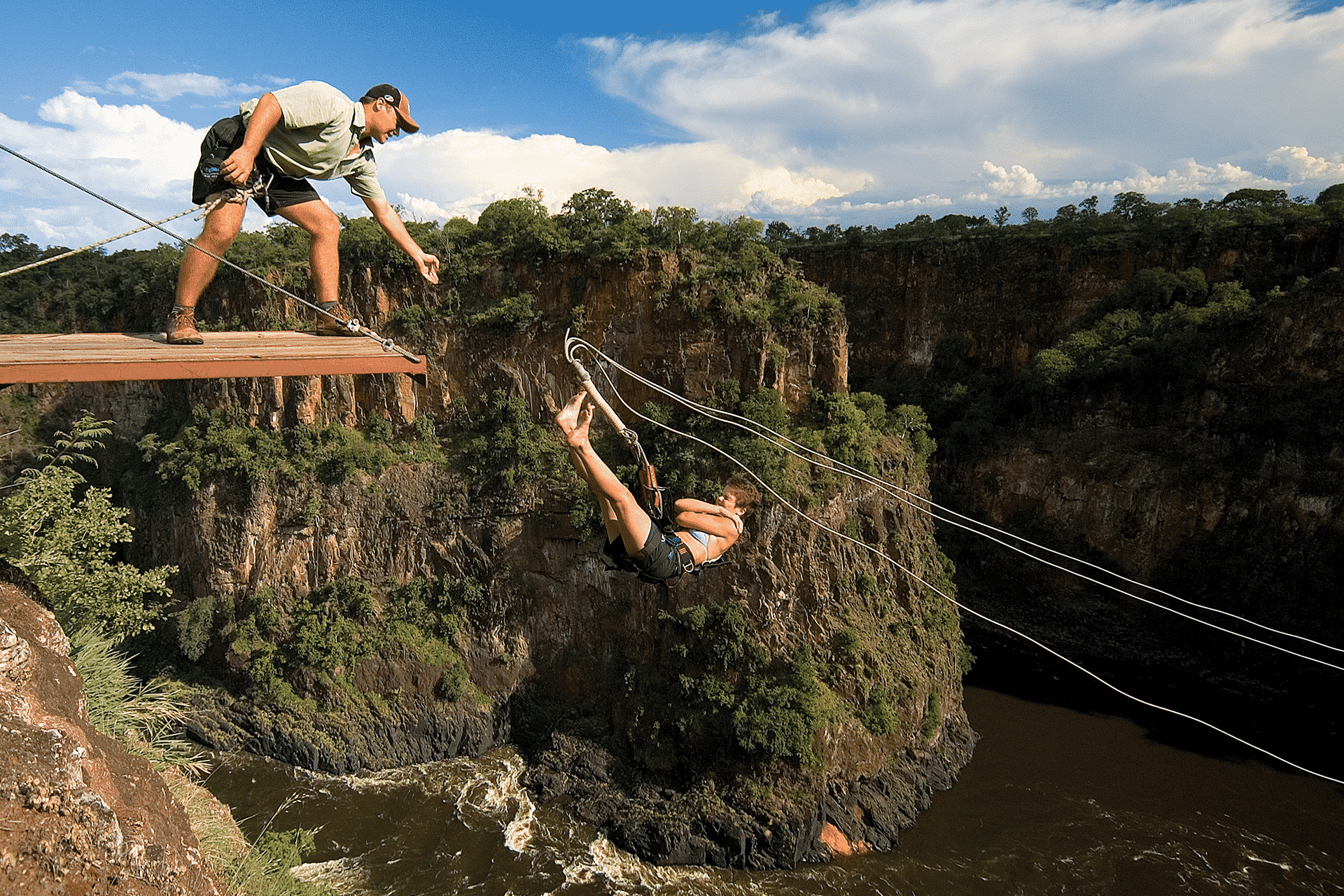 A woman launches off a platform at Victoria Falls