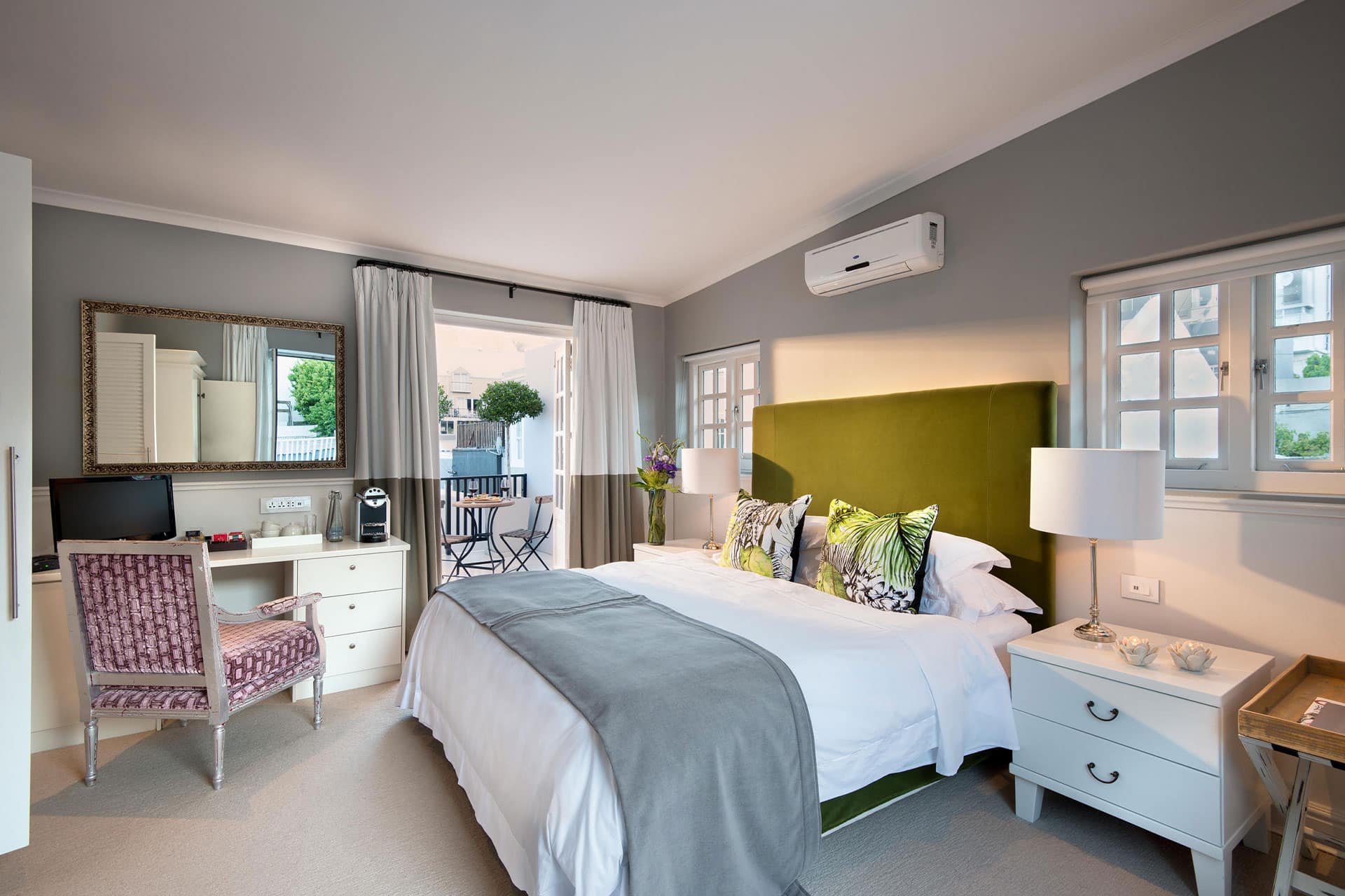 King size bed with writing desk in a luxury hotel room leading out onto a patio at the Cape Cadogan Boutique Hotel.