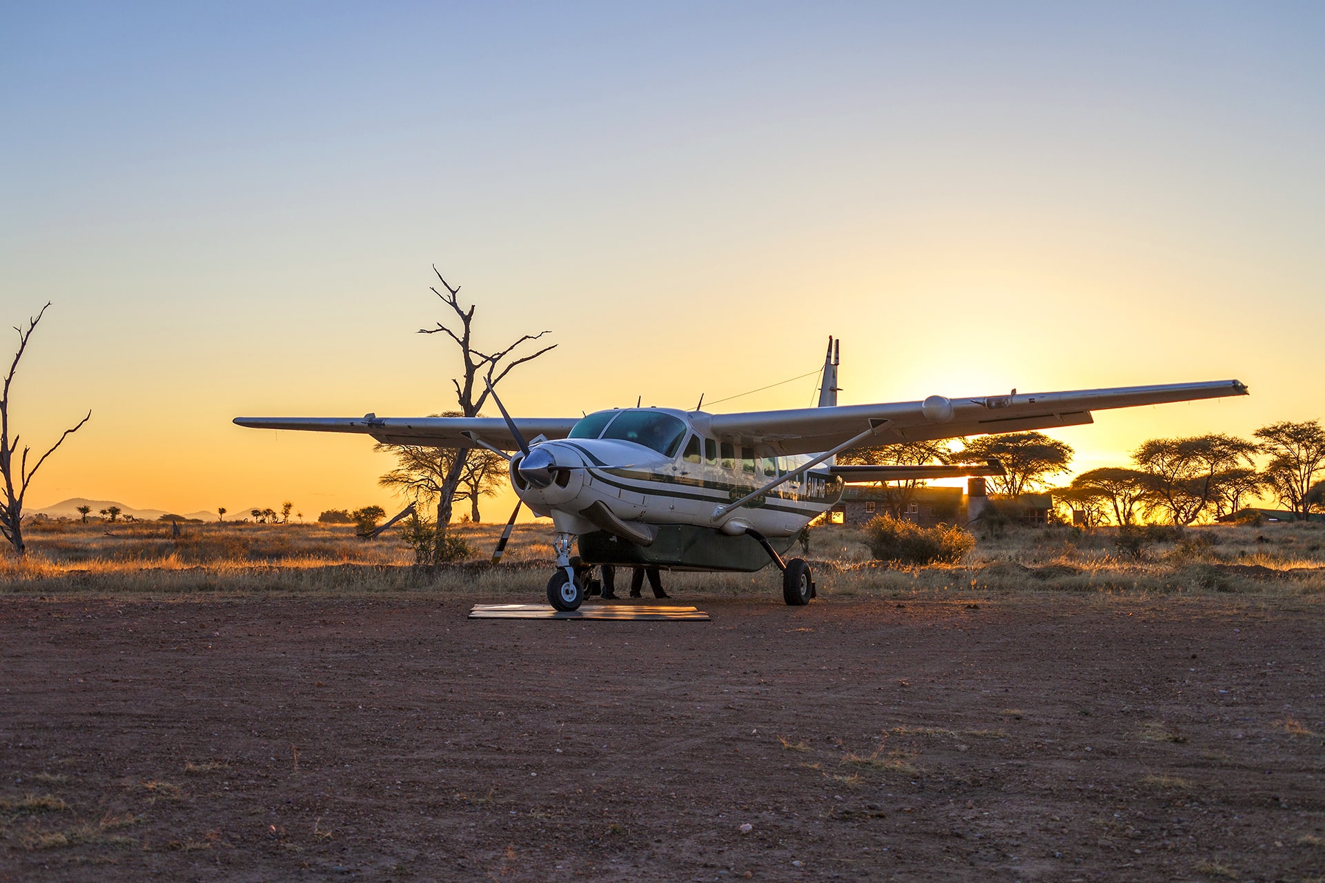 Light aircraft parked on a remote African airstrip at sunrise, ready for a fly-in safari offering time-saving transfers and breathtaking aerial views of the wilderness.