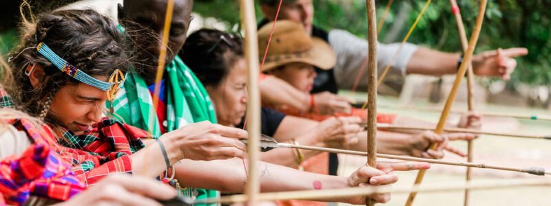 Archery practice in cultural clothing led by African safari tour guides in Kenya.