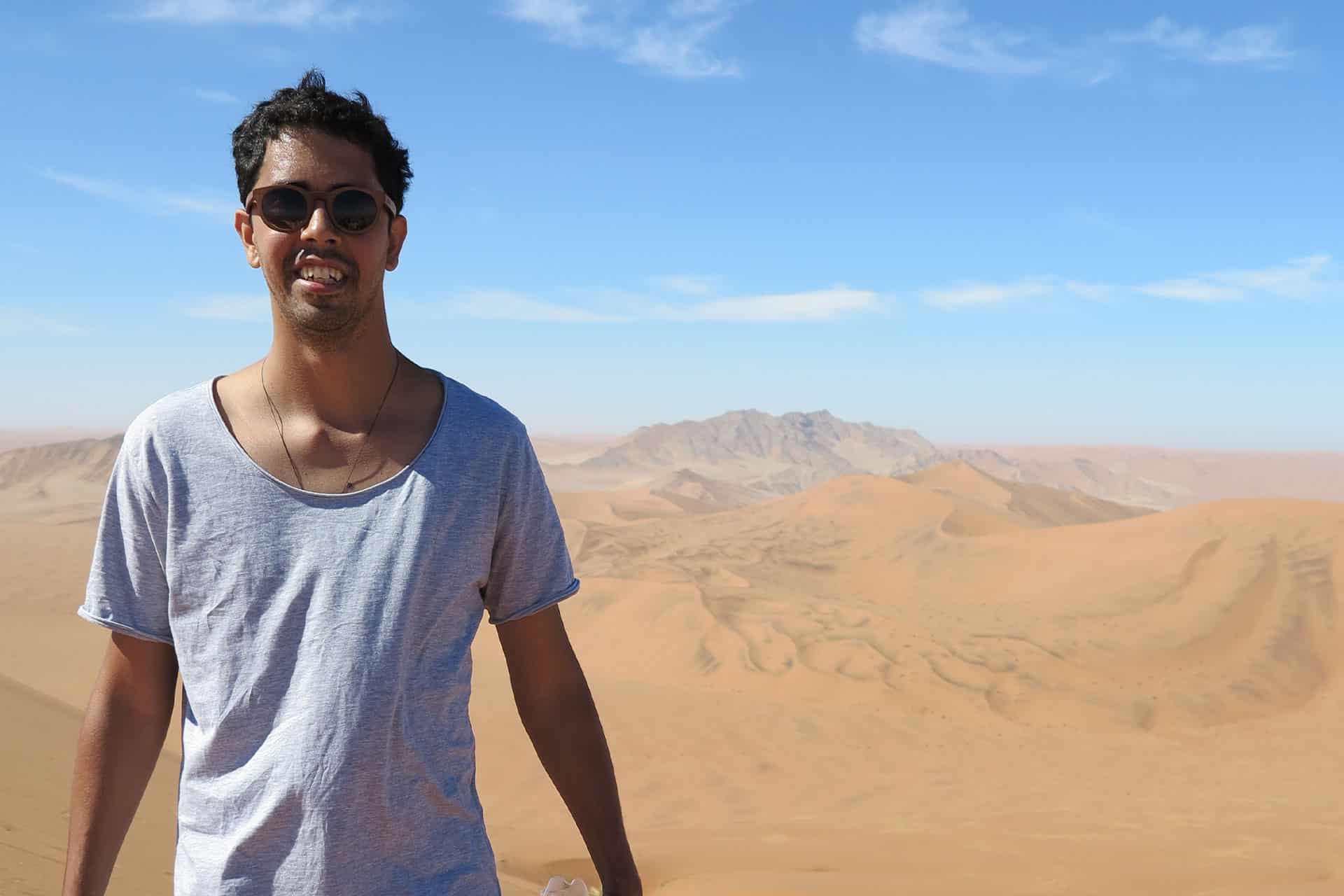 A man standing on a sand dune. 