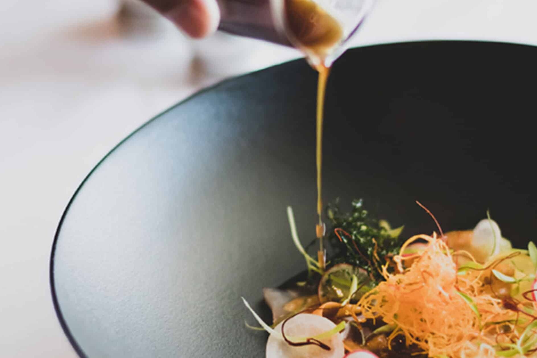 A chef pouring liquid onto a plated dish at Salsify at the Roundhouse &ndash; one of the top 10 fine dining restaurants in Cape Town. 
