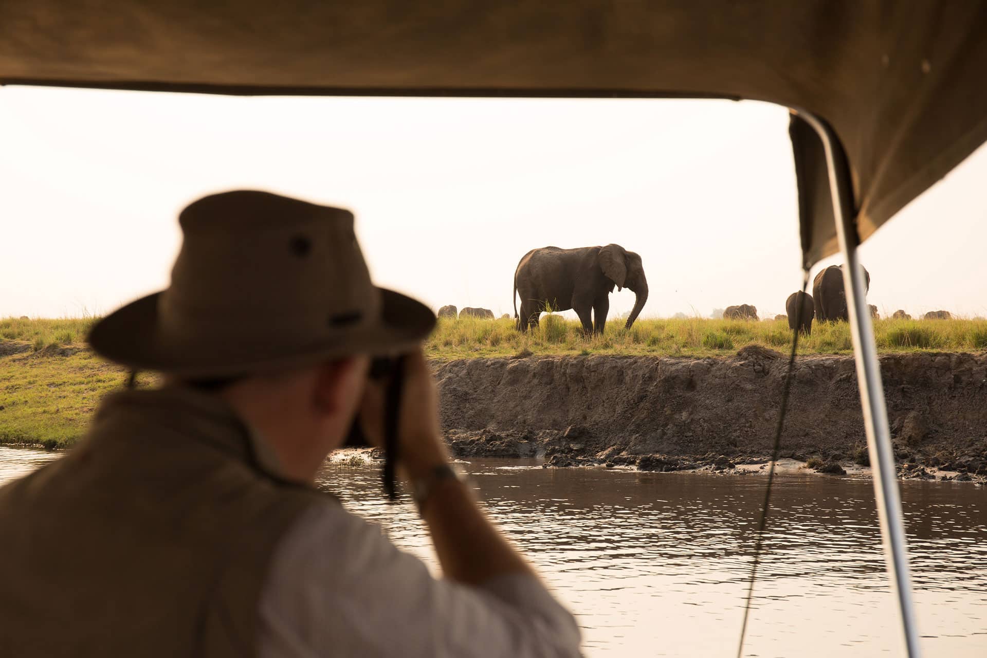 A man taking a photograph of an elephant from a boat on the Chobe River in Botswana - one of the top honeymoon destinations in Africa. 