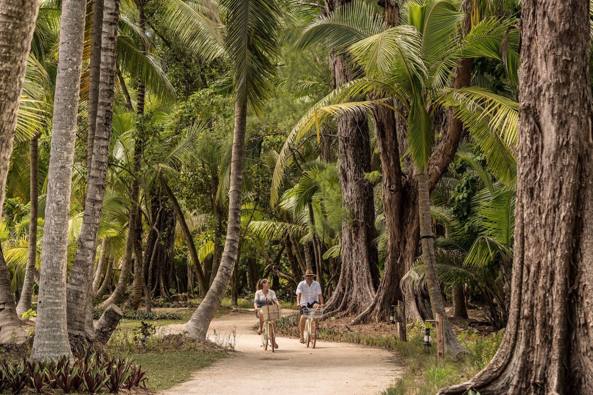 A honeymoon couple cycling at the Four Seasons Desroches Islands in the Seychelles.