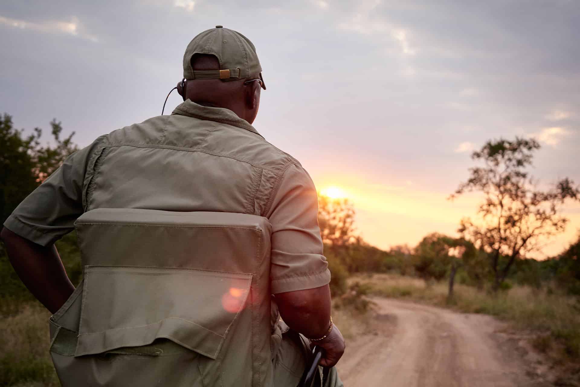 A tracker sitting at the front of a vehicle on a sunset game drive through the Thornybush Private Game Reserve at Waterside. 