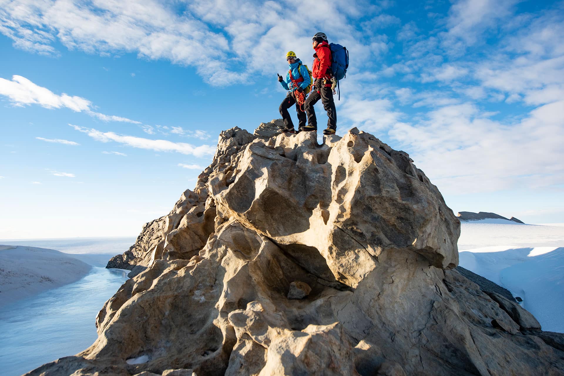 Two hikers on the summit of a mountain in Antarctica 