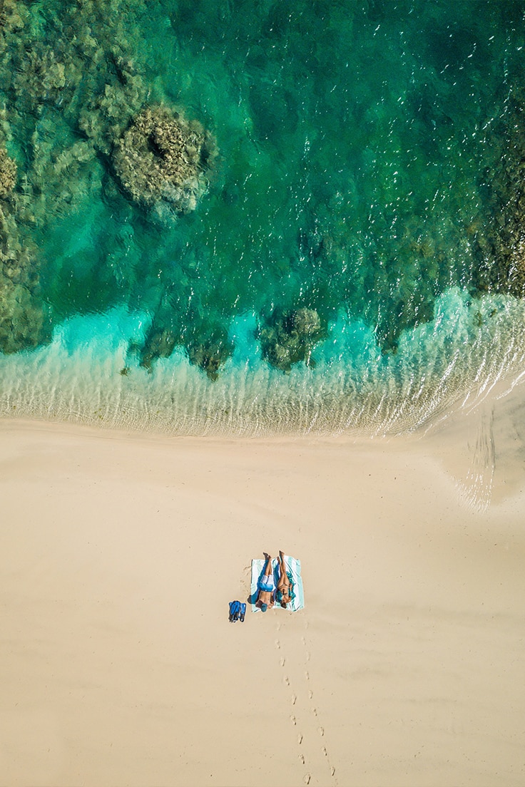 A couple relaxing on the beach after snorkeling at Miavana &ndash; a recommended experience for honeymoons in Africa. 