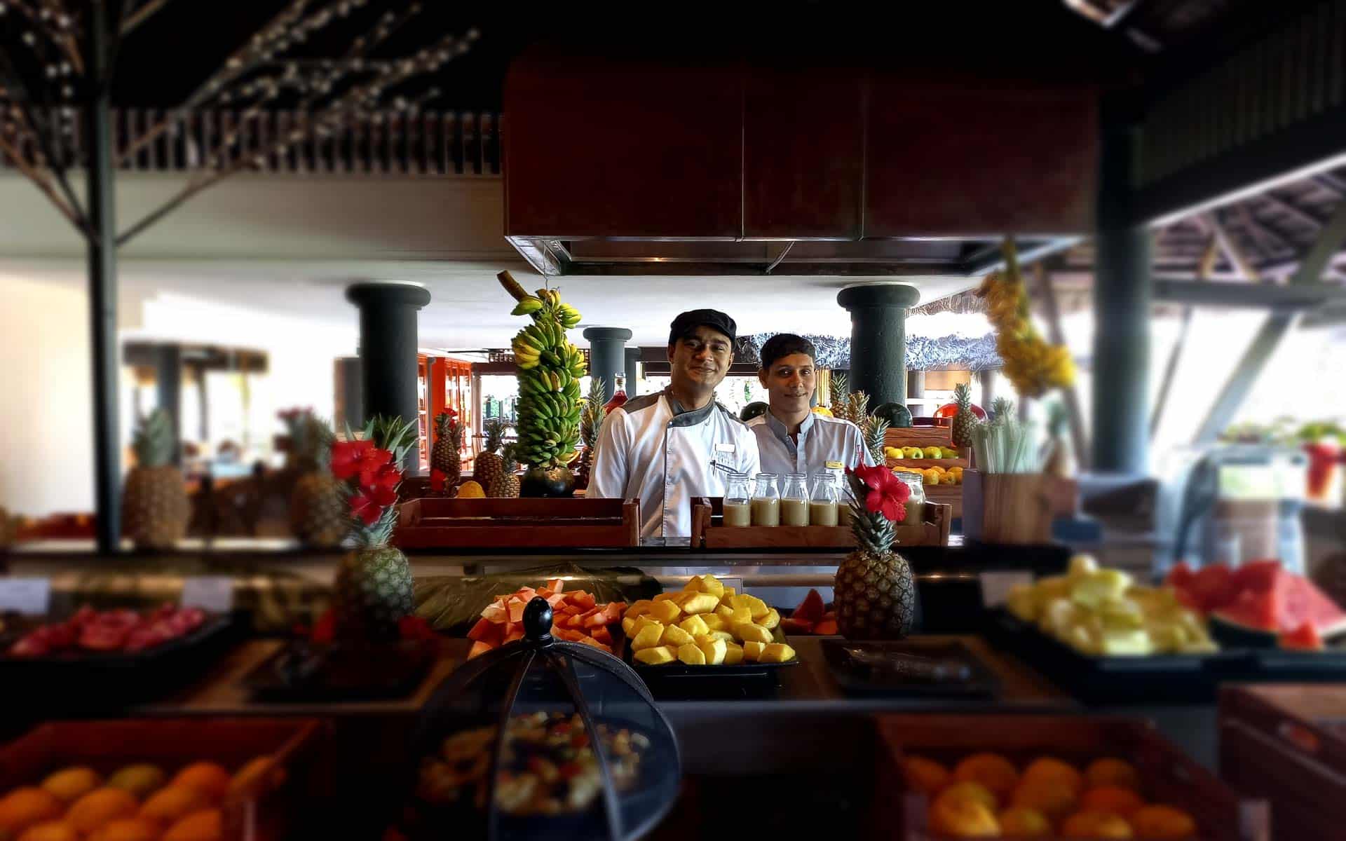 Two staff standing at the breakfast counter with lots of fruit in the foreground 