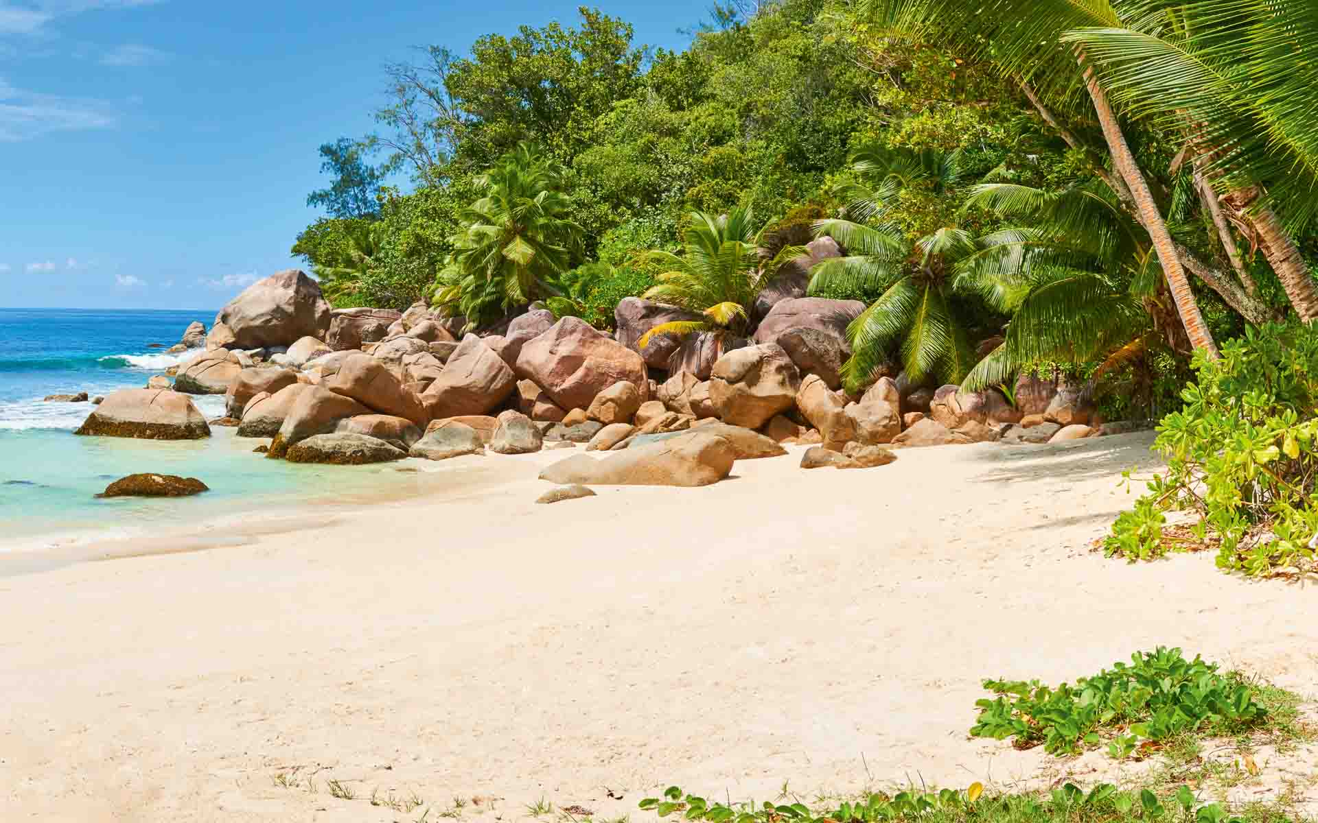 A guest being served a drink on a beautiful beach at Constance Lemuria in Seychelles. 