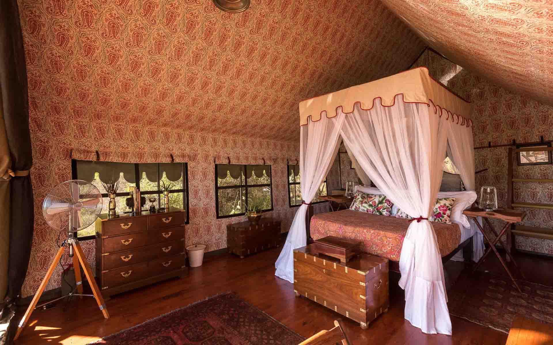 The interior of a luxury double tent with an antique 4 poster bed frame at Duke&rsquo;s Camp