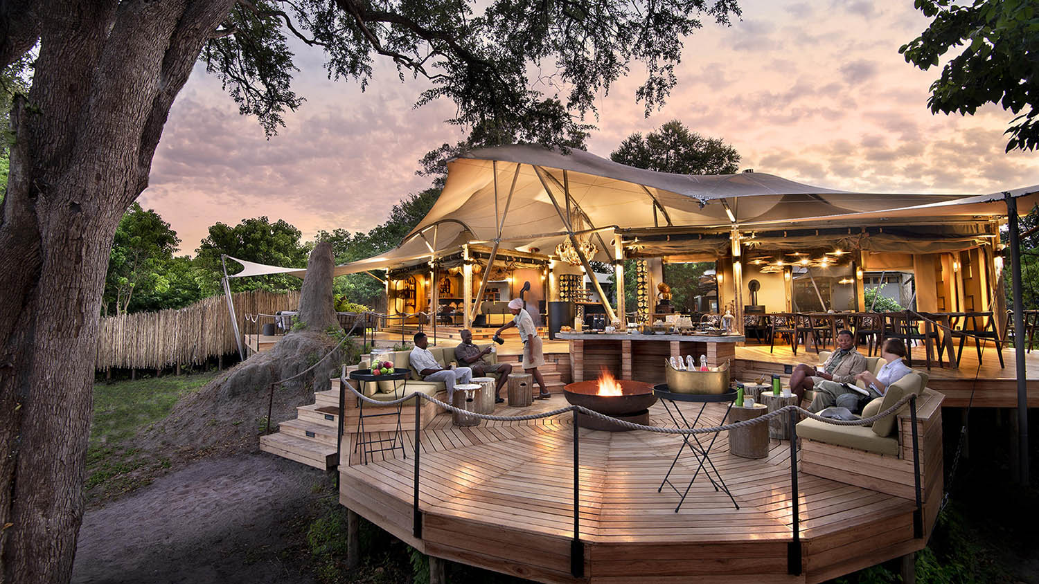 People sitting on deck in bush at Khwai Leadwood with Ker & Downey Africa