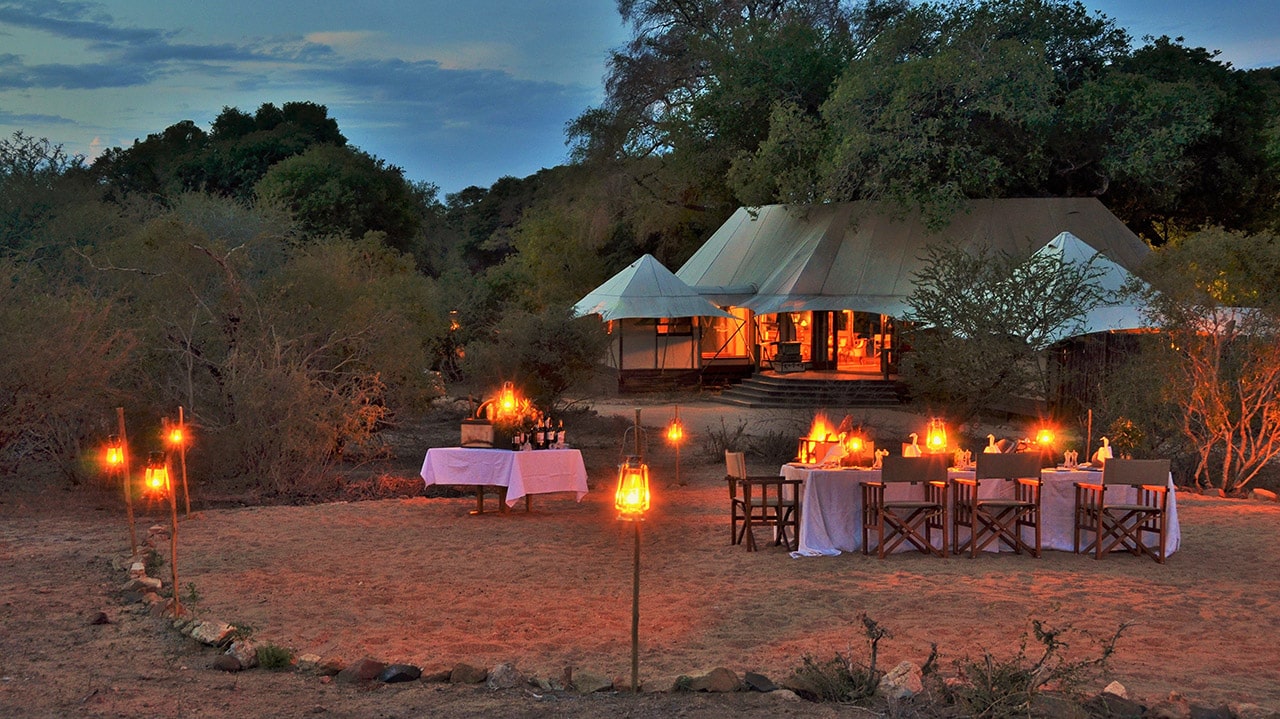 Chairs and table at night in front of tent with Ker & Downey Africa