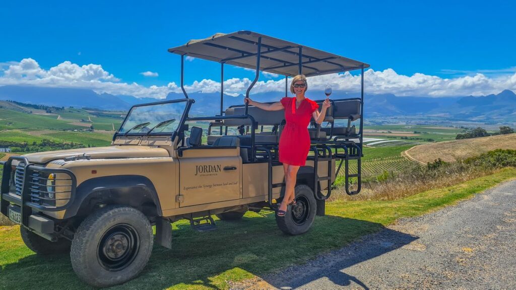 Woman on safari vehicle in front of mountains and vineyards with Ker & Downey® Africa