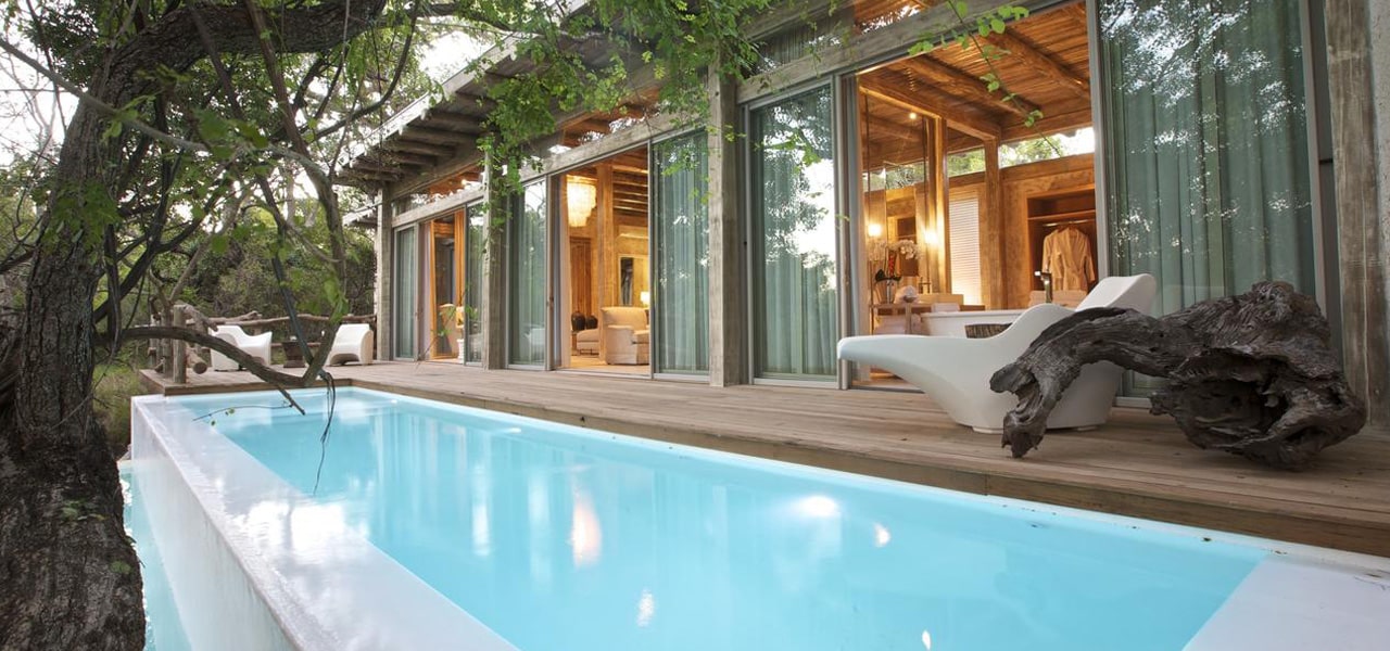 A private safari pool at Kapama Karula at dusk with a Kapama Karula suite in the background