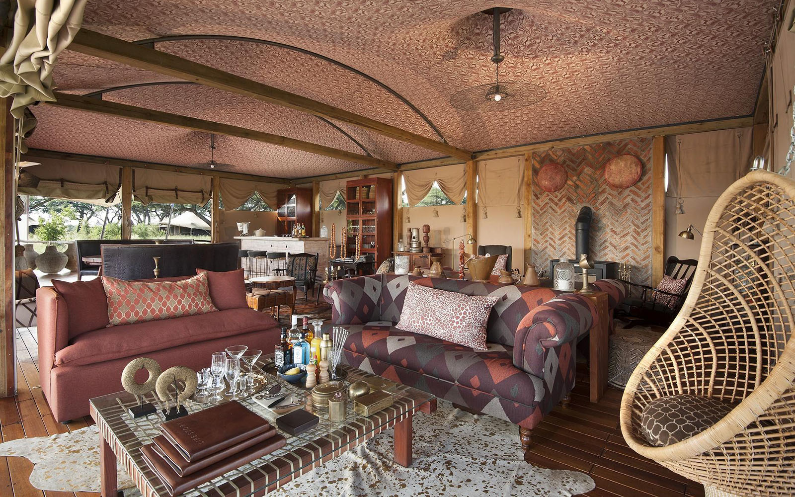 Colorful couches in the indoor lounge with fireplace at Somalisa Camp with Ker & Downey Africa